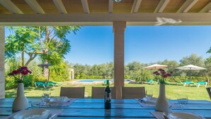 An outdoor dining area with tables set for two, overlooking a pool and garden. - Mercader - Villa With Private Pool In Alcúdia (Alcúdia, Illes Balears)
