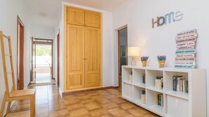 A hallway with a wooden wardrobe, a white bookshelf with books and decorative items, and a 'Home' sign on the wall.