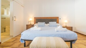 A hotel room with a large bed, two bedside tables with lamps, a wooden headboard, and a bench with a towel.