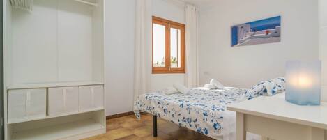 Een slaapkamer met een bed, een kledingkast, een raam en een plafondventilator.