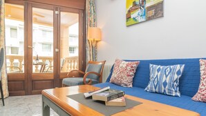 Un salon chaleureux avec un canapé bleu, une table basse en bois et une vue sur le balcon.