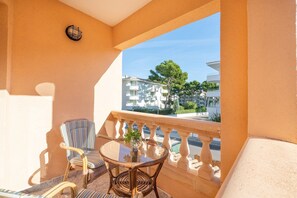 A balcony with a round table, striped chair, and a potted plant. - Casa Miriam - Apartment In Cala Lliteres (Cala Ratjada, Illes Balears)