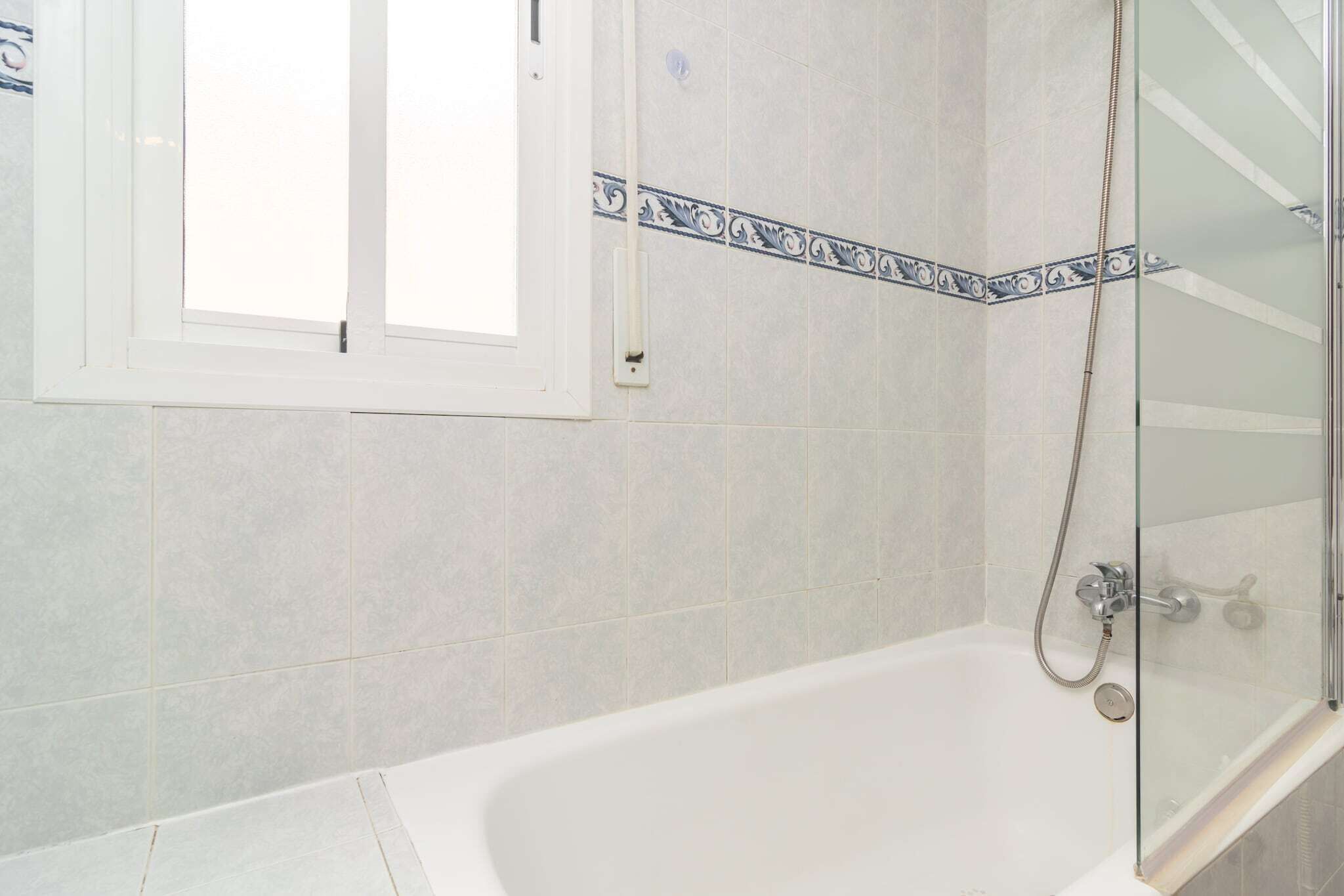 A bathroom with a bathtub, a shower, and a window.