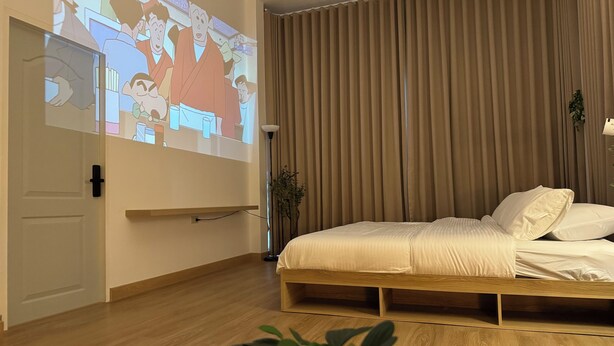A bedroom with a bed, a projection screen, and a plant. - Charming 2-bedroom house near natural  Hotspring with WiFi and AC in Ranong  (Mueang Ranong ,)
