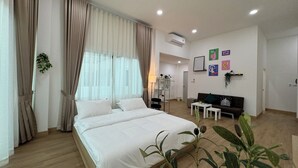 A hotel room with a large bed, a sofa, a small table, and a plant. - Charming 2-bedroom house near natural  Hotspring with WiFi and AC in Ranong  (Mueang Ranong ,)