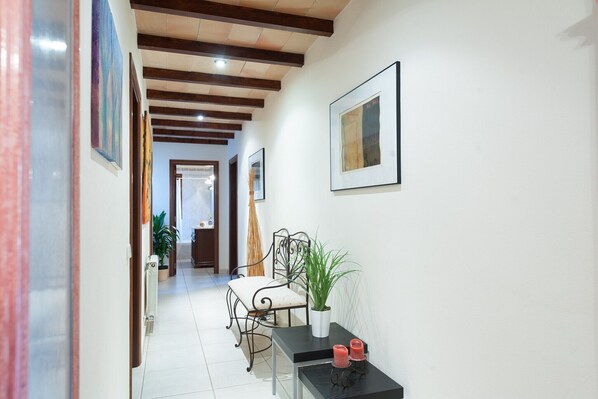 A hallway with a chair, a table with candles, and a potted plant. - Ca Na Granada - Villa With Private Pool In Muro (Muro, Illes Balears)