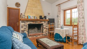 Ein Wohnzimmer mit Kamin, blauem Sofa, Holztisch und einem Fenster mit Vorhängen.
