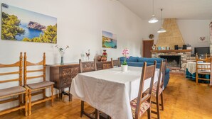 Ein Essbereich mit Tisch für vier Personen, Holzsesseln, einer Couch und einem Kamin.