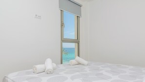 Ein Hotelzimmer mit Bett, Fenster mit Meerblick und Steckdose an der Wand.