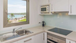 Eine Küche mit integriertem Mikrowellenherd, Spüle und Fenster mit Blick auf einen Strand.