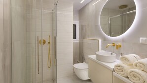 A modern bathroom with a glass-enclosed shower, a white sink, and a round mirror. - Millerou16-18·Elegant minimal studio in Kerameikos (Athens)