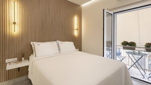 A modern hotel room with a large bed, a bedside table with a lamp, and a view of the balcony with potted plants. - Millerou16-18·Elegant minimal studio in Kerameikos (Athens)