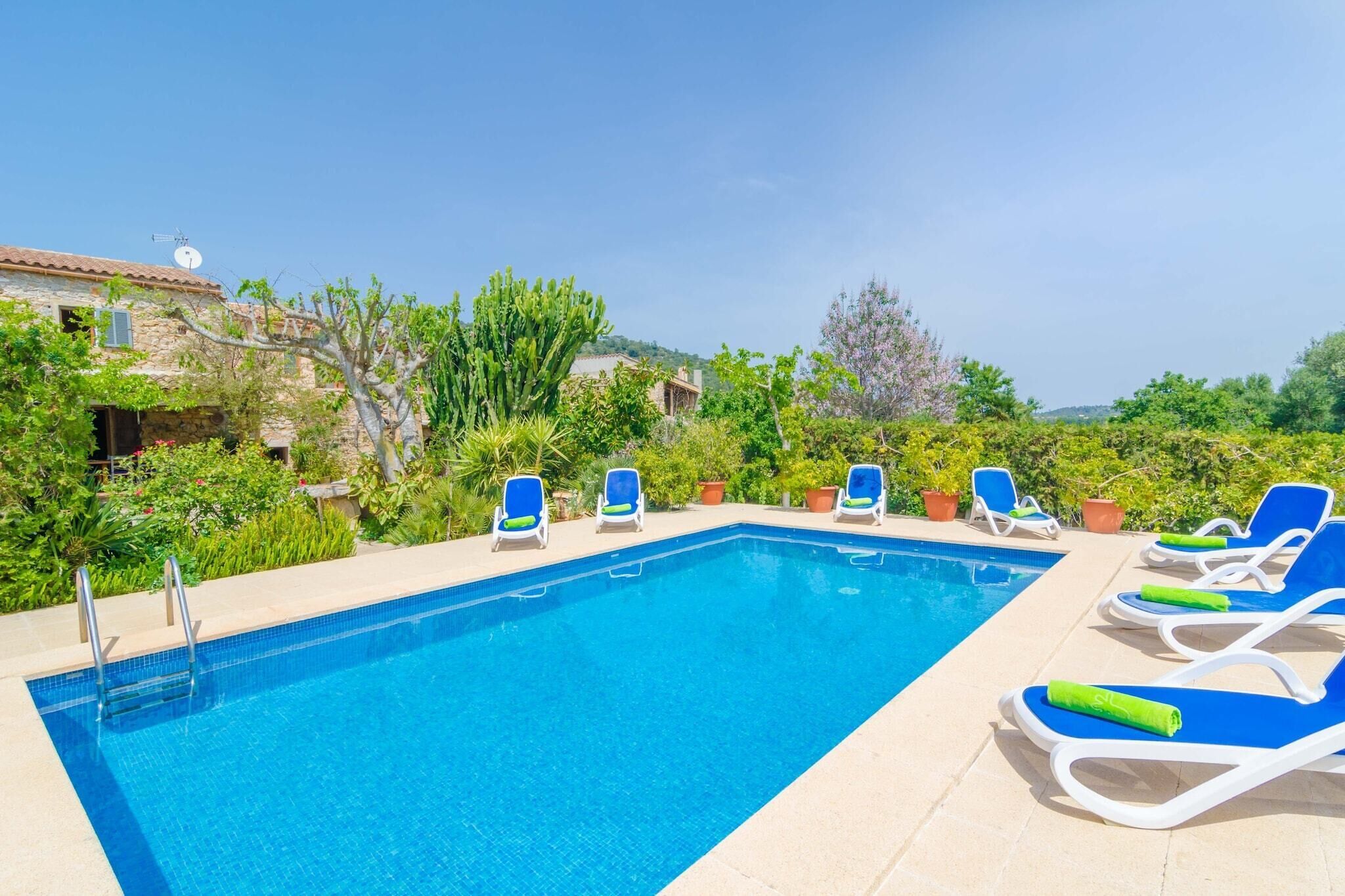 A rectangular swimming pool with clear blue water, surrounded by lounge chairs with blue cushions and green towels.