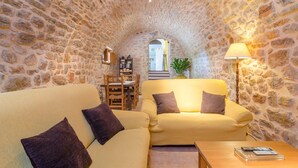 A cozy room with stone walls, a yellow sofa, a wooden coffee table, and a lamp.