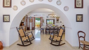 A dining area with a high arched doorway, wooden rocking chairs, and a table set for six. - Son Real - Villa With Private Pool In Sencelles (Sencelles, Illes Balears)
