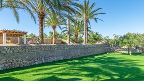 A stone wall with a pergola and chairs, palm trees, and a well-maintained lawn. - Son Real - Villa With Private Pool In Sencelles (Sencelles, Illes Balears)