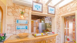 A kitchen with stone walls, wooden counter, and wicker furniture.