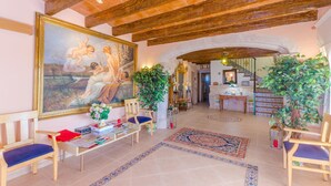 A spacious lobby with a large painting, wooden beams, and a tiled floor.