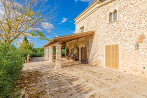 A stone building with a covered patio, arched doorways, and a tiled walkway. - Na Pont - Villa With Private Pool In Campos (Campos, Illes Balears)