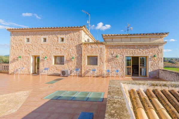 A stone building with a tiled patio, outdoor seating, and a view of the countryside. - Na Pont - Villa With Private Pool In Campos (Campos, Illes Balears)