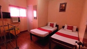 A room with two beds, a TV, and a window with curtains.