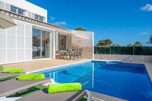 A modern pool area with a clear blue pool, lounge chairs, and a dining table with chairs. - Domus Genti - Villa With Private Pool. Free Wifi (Son Serra De Marina, Illes Balears)