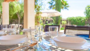 A table set outdoors with clear glassware, plates, and cutlery.