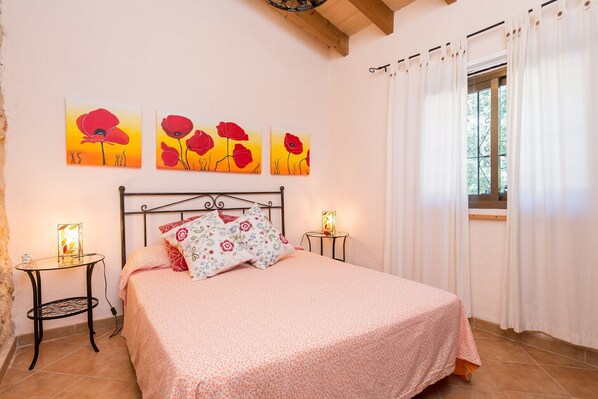 Une chambre à coucher comprenant un lit, deux tables de chevet et trois tableaux accrochés au mur.