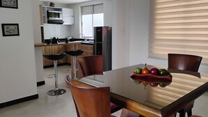 A modern kitchen with a dining table, chairs, and a fruit bowl.