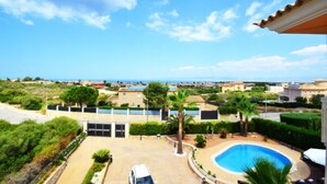 A residential area with a swimming pool, a parked car, and a view of the sea.