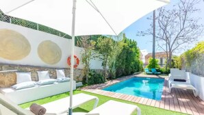 Ein Poolbereich mit Liegestuhl, Lounge-Sessel und kleiner Holzterrasse.
