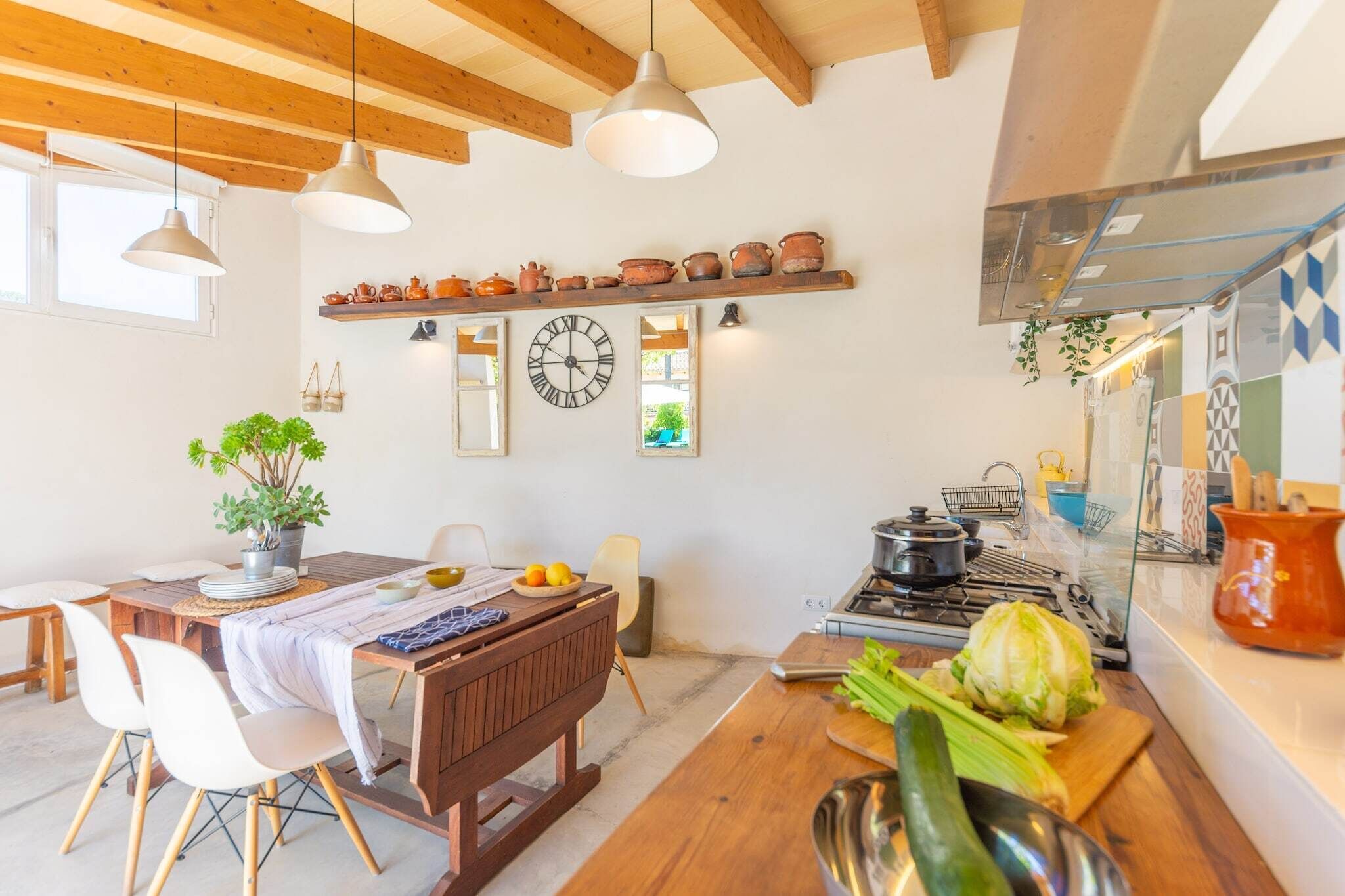 A kitchen with wooden beams, a stove, and a hanging plant.