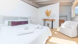 Ein modernes Schlafzimmer mit einem großen Bett, einem weißen Stuhl und einem kleinen Tisch mit einer Vase.