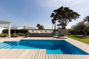 Relax by the pool surrounded by lush greenery and a comfortable seating area.
