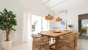 A dining area with a wooden table and wicker chairs, a potted plant, and pendant lighting. - Sa Blava - Villa With Private Pool. Free Wifi (, Illes Balears)