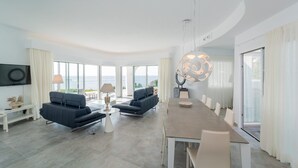 Un salon moderne avec un canapé, une table à manger et une grande fenêtre donnant sur la mer.