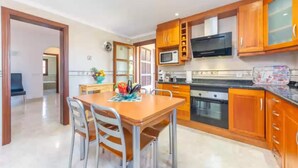 A modern kitchen with wooden cabinets, a microwave, and a dining area with a table and chairs.
