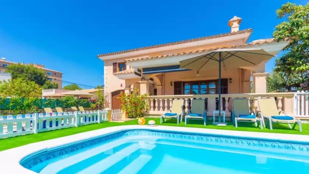 A two-story house with a swimming pool, a covered patio, and a white fence.