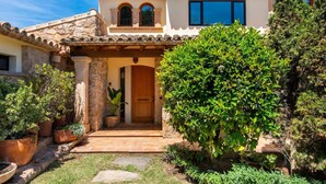 A Mediterranean-style house with a stone facade, a wooden door, and a tiled roof.
