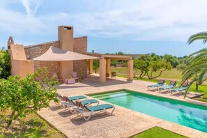 Uma área de piscina com espreguiçadeiras e um pergolado.
