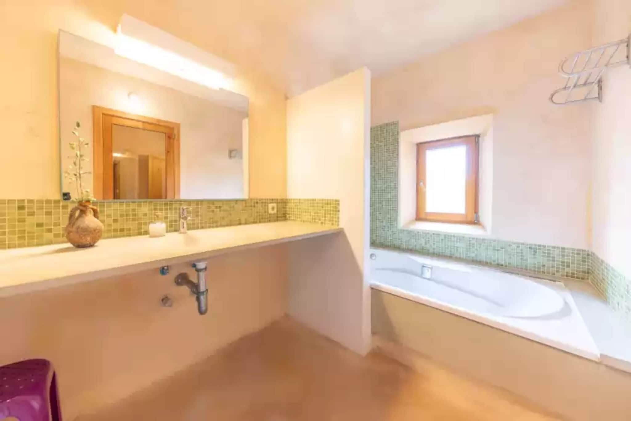 Une salle de bain avec un grand miroir, un lavabo et une baignoire.