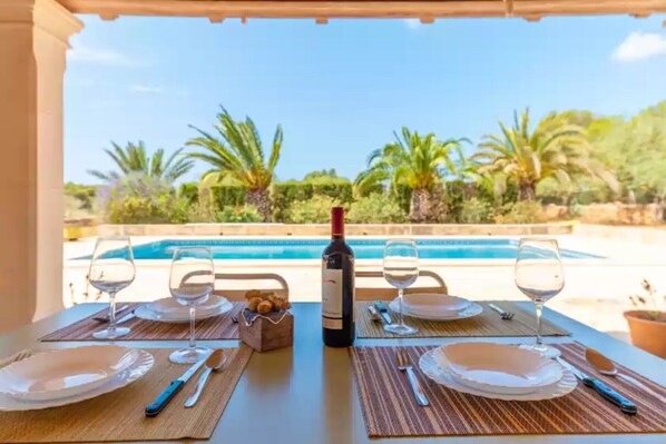 Enjoy al fresco dining with a view of the pool and lush surroundings.