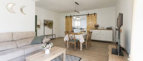 Ett modernt vardagsrum med en soffa, ett soffbord och en matplats med stolar och ett bord.