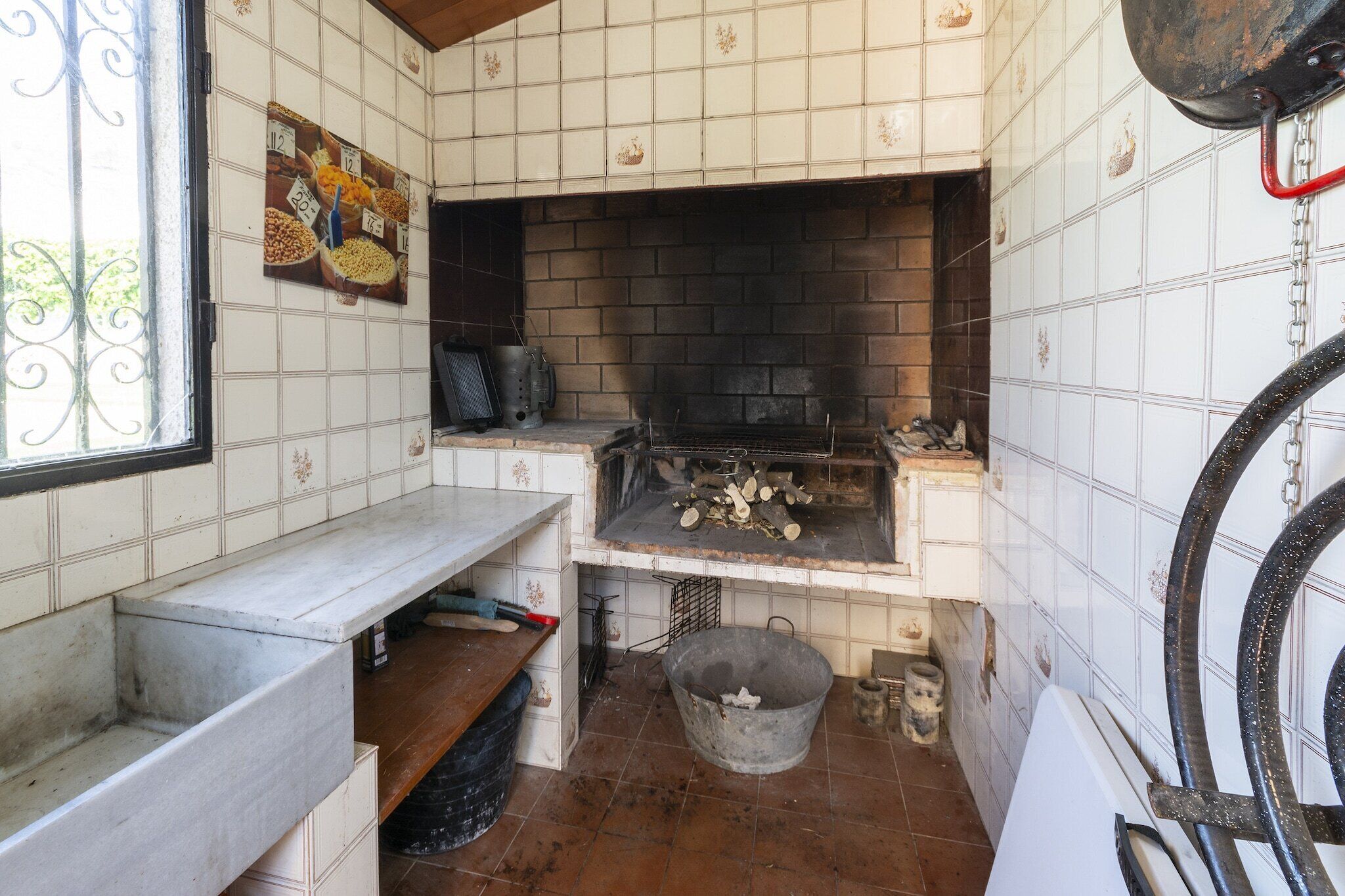 A kitchen with a tiled backsplash, a brick fireplace, and a window with a decorative iron grille.