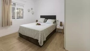 A bedroom with a bed, a nightstand, a ceiling fan, a window with curtains, and a wall clock. - Cova De L'aire - Villa With Private Pool In Barx (, Valencia)