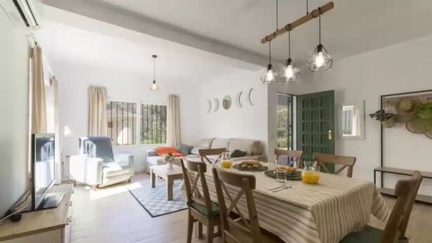 A dining area with a wooden table, chairs, and hanging pendant lights. - Cova De L'aire - Villa With Private Pool In Barx (, Valencia)