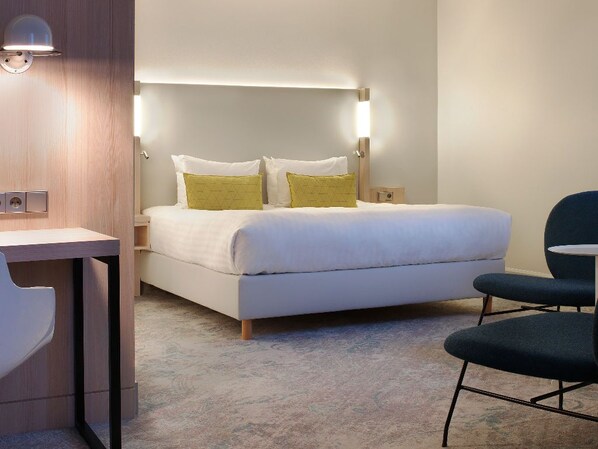 Ein modernes Hotelzimmer mit einem ordentlich bezogenen Bett, Nachttischen und einem Schreibtisch.