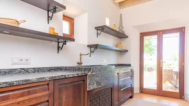 A kitchen with dark wooden cabinets, granite countertops, and black metal shelves. - Son Catxo - Villa With Private Pool In Búger (, Illes Balears)
