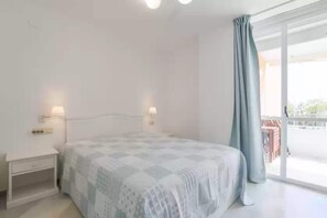 Un dormitorio con cama, lámparas de noche, una mesita de noche y vistas al exterior a través de un ventanal grande.