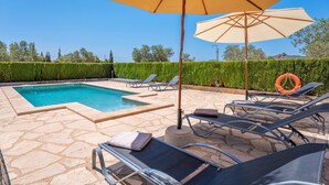 A swimming pool with lounge chairs and an umbrella.